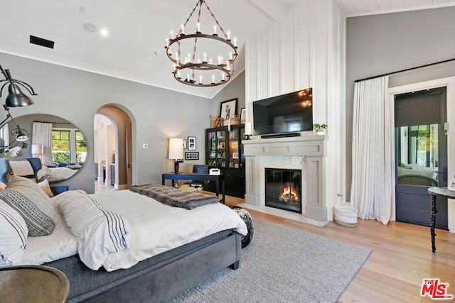 bedroom with lofted ceiling, a notable chandelier, connected bathroom, and light wood-type flooring