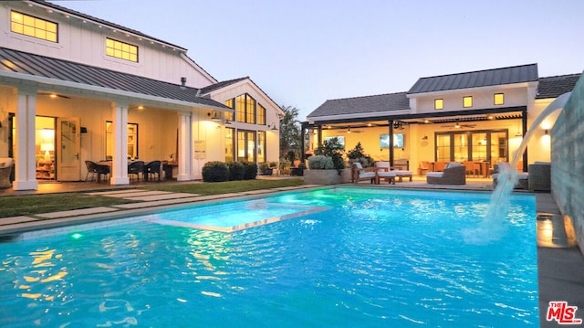 pool at dusk featuring ceiling fan, an outdoor living space, and a patio area