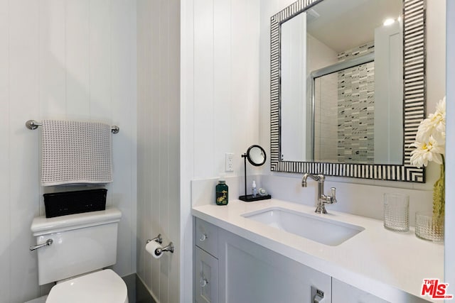 bathroom with toilet, vanity, and a shower with shower door