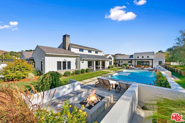 view of swimming pool featuring pool water feature, a patio area, and a fire pit