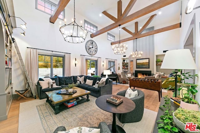 living room with beam ceiling, light wood-type flooring, a chandelier, and high vaulted ceiling