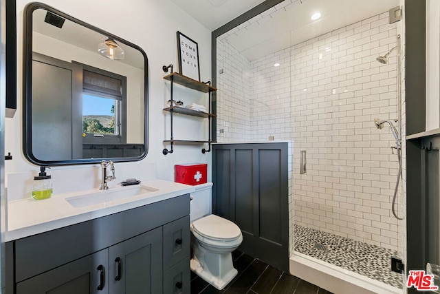 bathroom featuring a shower with door, vanity, and toilet