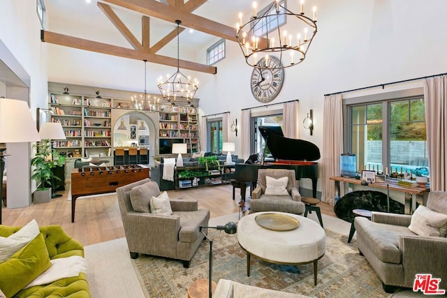 living room with a high ceiling, a chandelier, light hardwood / wood-style floors, and beamed ceiling