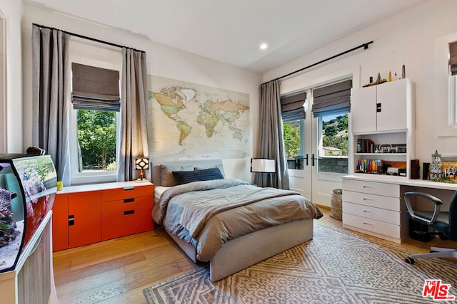 bedroom featuring built in desk, light hardwood / wood-style floors, and french doors