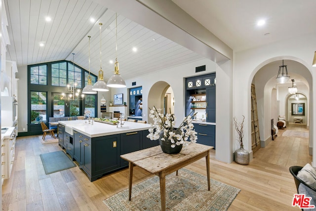 kitchen with light hardwood / wood-style floors, a kitchen island with sink, hanging light fixtures, and wooden ceiling