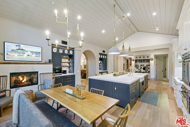 dining area with a fireplace, high vaulted ceiling, light hardwood / wood-style flooring, and wooden ceiling