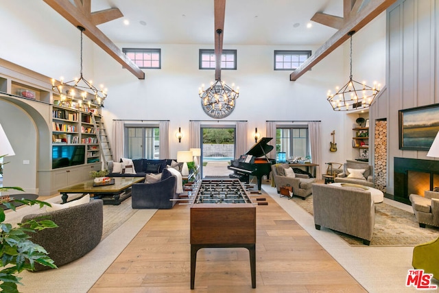 living room with a high ceiling, an inviting chandelier, and light hardwood / wood-style flooring