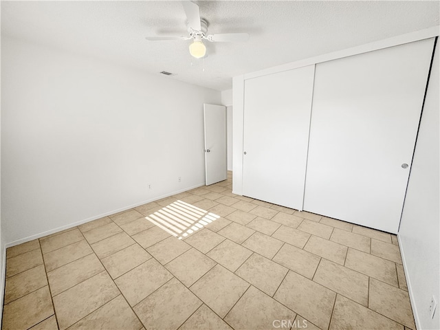 unfurnished bedroom with ceiling fan, a textured ceiling, and a closet