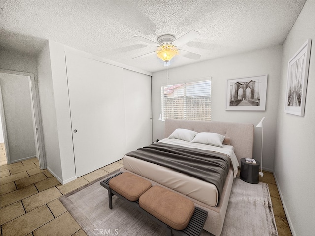 tiled bedroom with ceiling fan and a textured ceiling