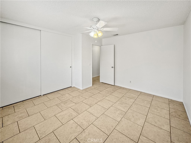 unfurnished bedroom featuring ceiling fan, a textured ceiling, a closet, and light tile patterned flooring