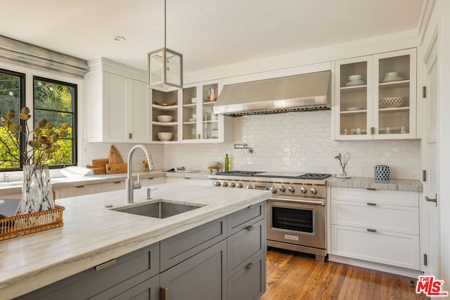 kitchen with sink, wall chimney exhaust hood, dark hardwood / wood-style floors, light stone countertops, and high end stove