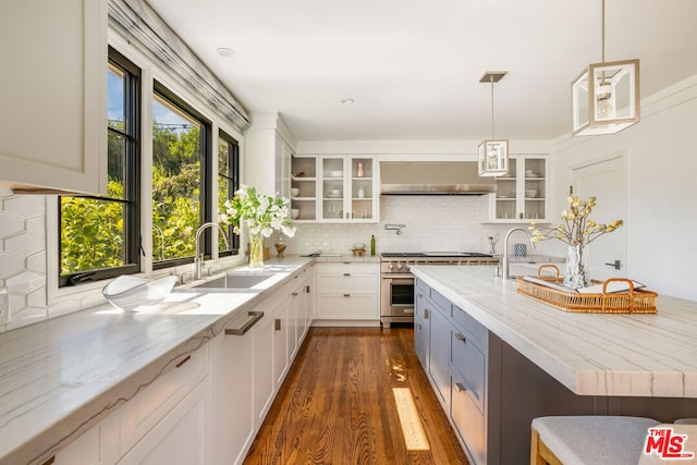 kitchen with stainless steel range, sink, light stone counters, pendant lighting, and white cabinets