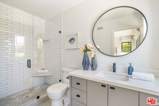 bathroom with vanity, toilet, and a shower with shower door