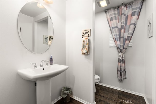 bathroom with wood-type flooring, toilet, and sink