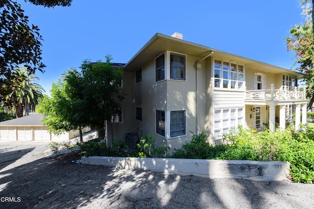 view of front facade with a balcony, a garage, and central AC