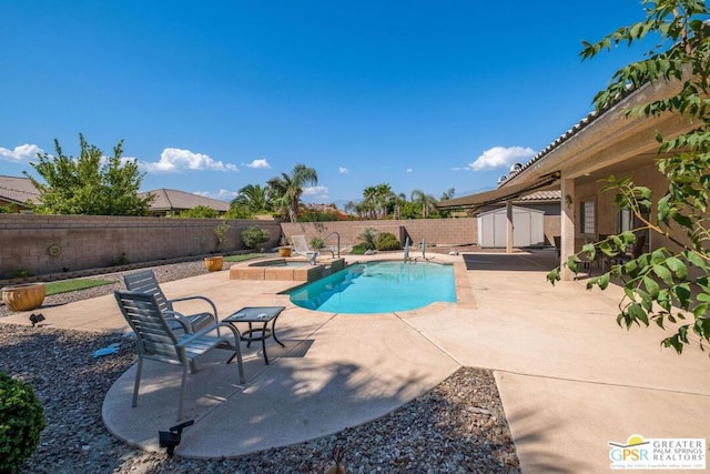 view of pool featuring an in ground hot tub, a patio area, and a storage shed