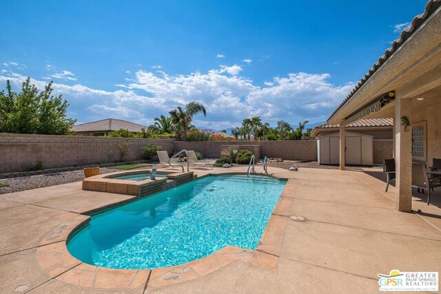 view of swimming pool with a shed, an in ground hot tub, and a patio