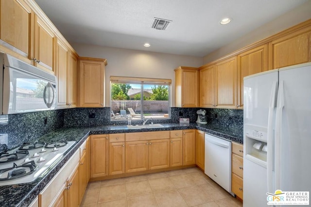 kitchen featuring backsplash, white appliances, light tile patterned floors, and sink