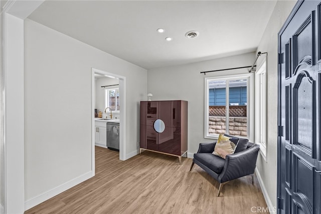 sitting room with light wood-type flooring, sink, and a wealth of natural light