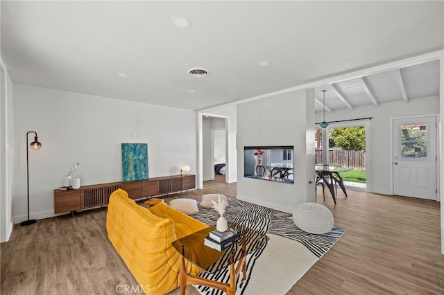 living room with lofted ceiling with beams and hardwood / wood-style flooring