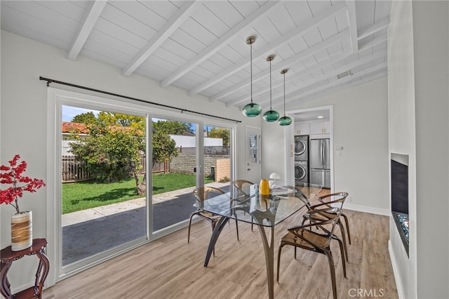 sunroom featuring vaulted ceiling with beams, wood ceiling, and stacked washer / dryer