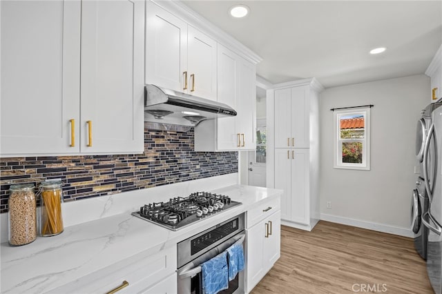 kitchen featuring white cabinets, stainless steel appliances, baseboards, decorative backsplash, and under cabinet range hood