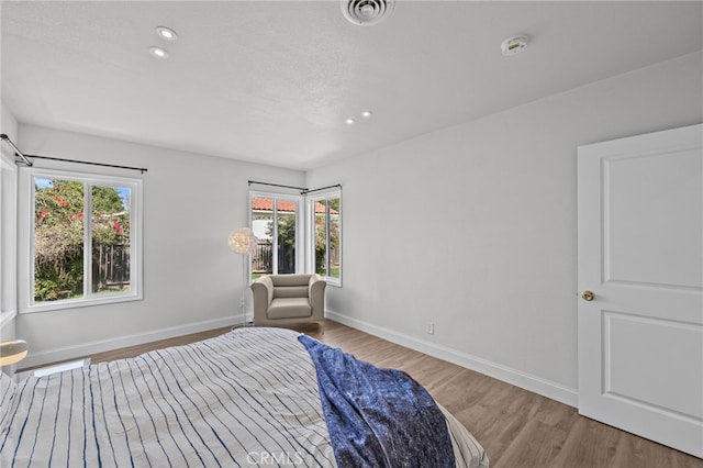 bedroom with multiple windows and light wood-type flooring