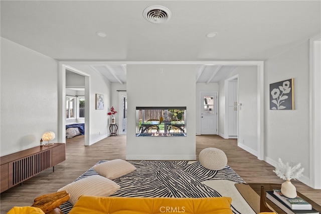 living room with light wood-type flooring, a healthy amount of sunlight, and beam ceiling