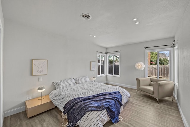 bedroom with multiple windows, a textured ceiling, and light wood-type flooring