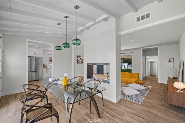 dining area with light hardwood / wood-style flooring and beam ceiling