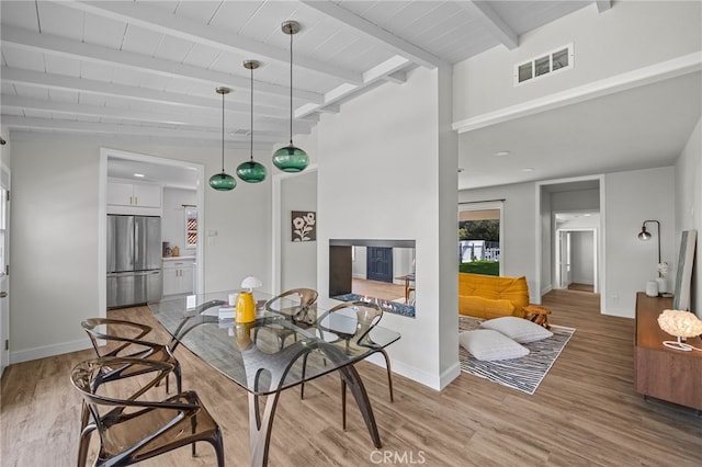 dining area featuring visible vents, baseboards, light wood-style flooring, and beam ceiling
