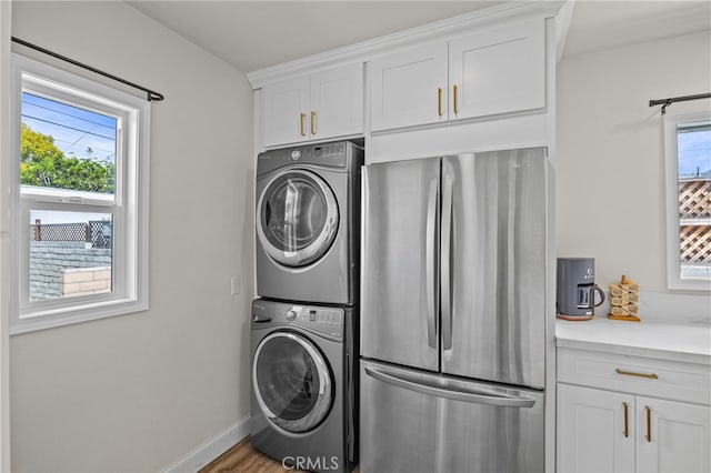 laundry area featuring stacked washer / drying machine and hardwood / wood-style flooring