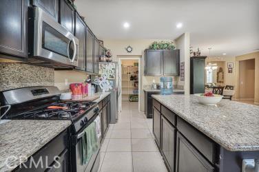 kitchen with a center island, light stone countertops, stainless steel appliances, and light tile patterned floors