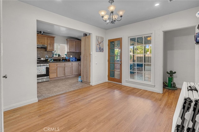 kitchen with tasteful backsplash, pendant lighting, an inviting chandelier, light hardwood / wood-style flooring, and stainless steel range