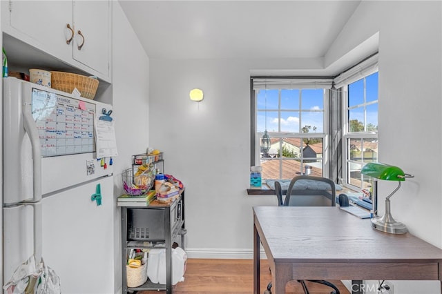 kitchen featuring white cabinets, white refrigerator, light wood-type flooring, and a healthy amount of sunlight