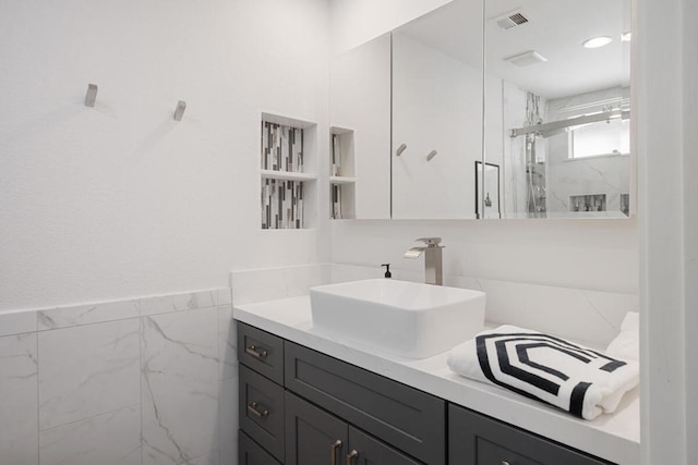 bathroom featuring tile walls, vanity, and a shower with shower door