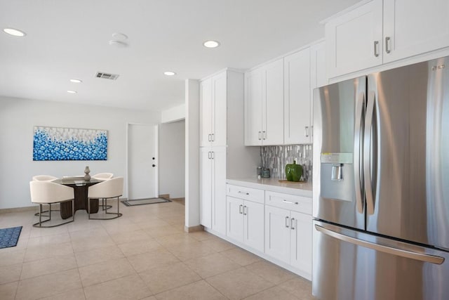 kitchen featuring white cabinetry, light tile patterned floors, stainless steel fridge with ice dispenser, and backsplash