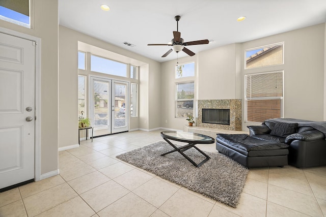 tiled living room with ceiling fan, a healthy amount of sunlight, and a premium fireplace