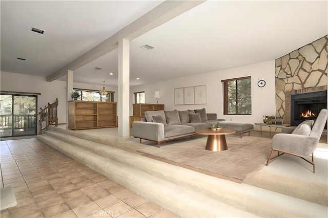 living room featuring a stone fireplace, a healthy amount of sunlight, light tile patterned flooring, and beamed ceiling