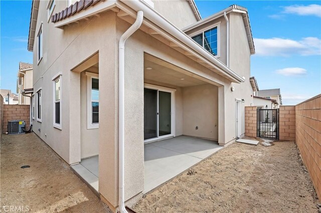 back of property with central AC unit and a patio