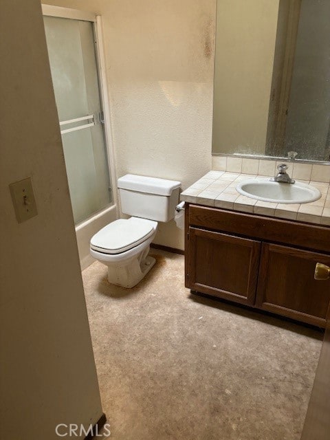 full bathroom with combined bath / shower with glass door, vanity, and toilet