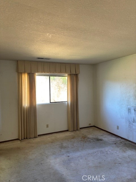 carpeted spare room with a textured ceiling