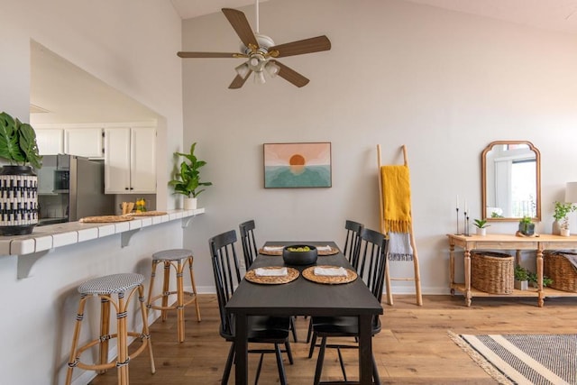 dining area with ceiling fan, lofted ceiling, and light wood-type flooring