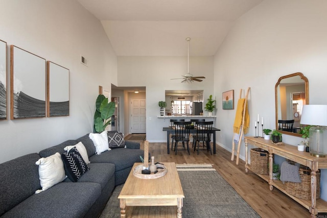 living room with hardwood / wood-style floors, high vaulted ceiling, and ceiling fan