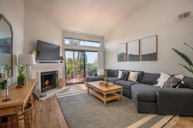 living room with a fireplace, light hardwood / wood-style flooring, and a high ceiling