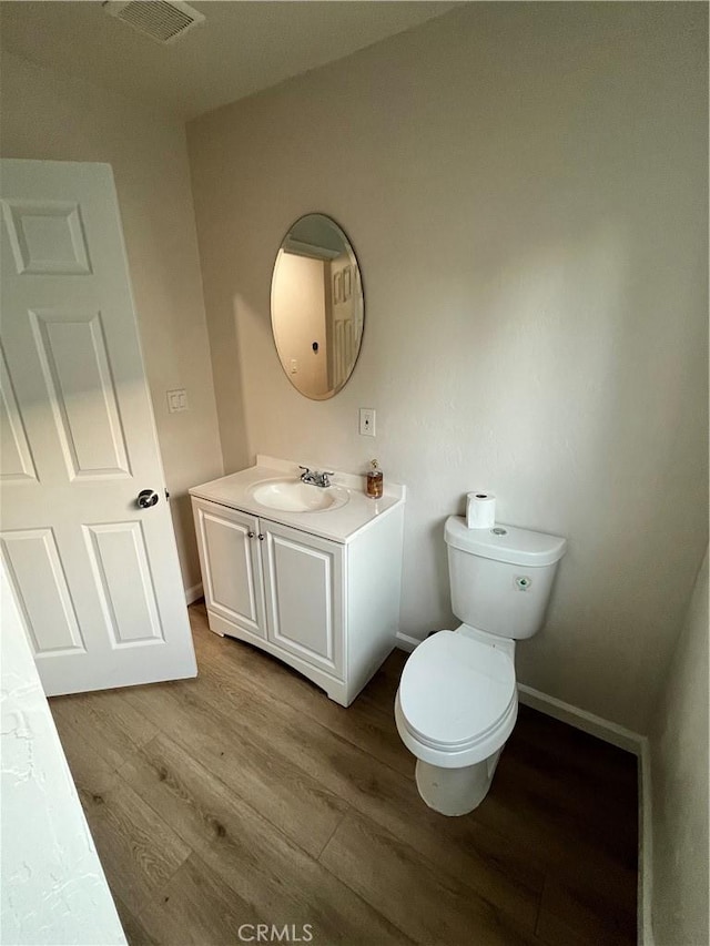 bathroom with toilet, vanity, and hardwood / wood-style flooring