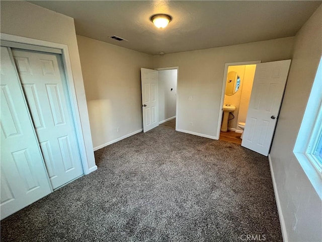 unfurnished bedroom with dark colored carpet and a closet