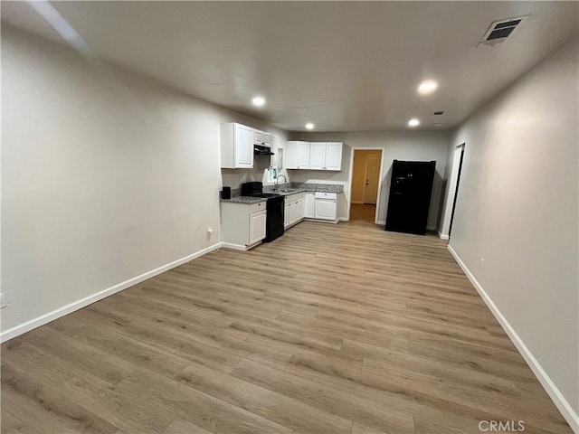 kitchen with black stove, light wood-type flooring, white cabinetry, and sink