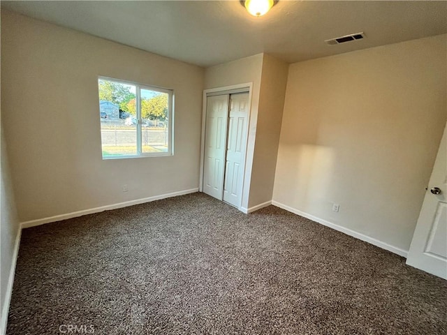 unfurnished bedroom with a closet and dark colored carpet