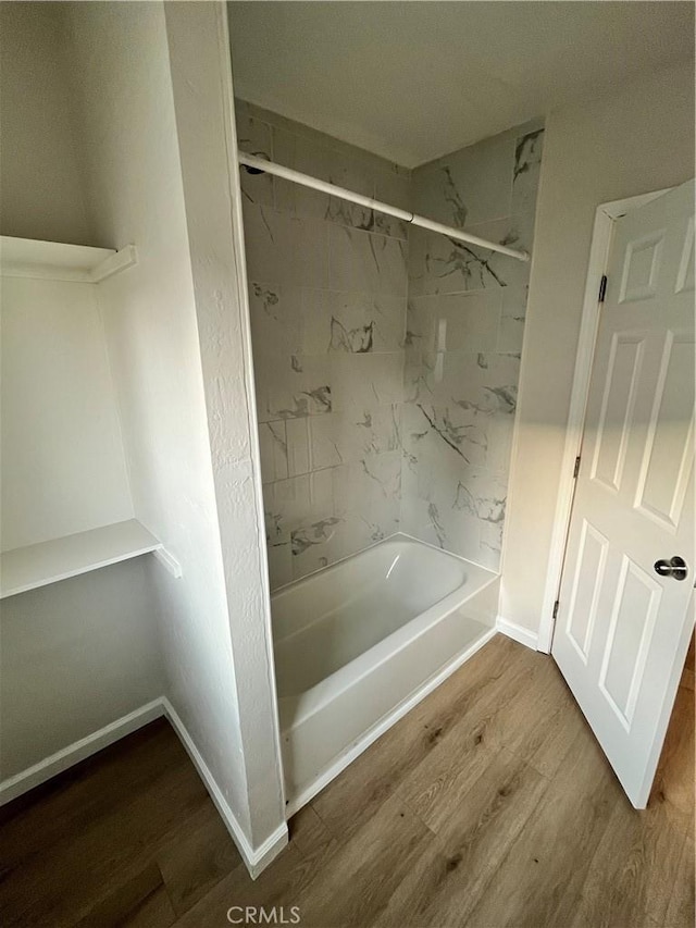 bathroom featuring wood-type flooring and tiled shower / bath